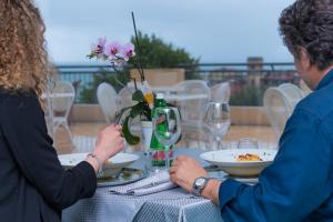 a man and woman sitting at a table with wine glasses at Hotel America in Marina di Camerota