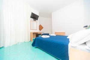 a bedroom with a blue bed and a desk at Hotel America in Marina di Camerota