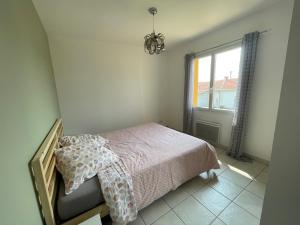 Schlafzimmer mit einem Bett und einem Fenster in der Unterkunft L'ambre salée in Gujan-Mestras