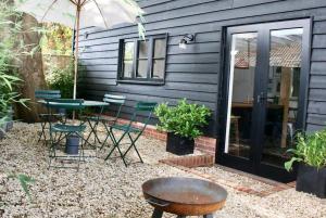 un patio con mesa, sillas y sombrilla en The Post Barn, beautiful barn conversion 10mins from Winchester en Sparsholt