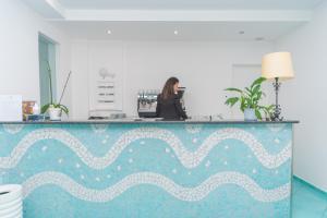 a woman standing behind a counter in a room at Hotel America in Marina di Camerota