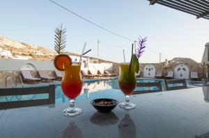 Arkasa Bay Hotel في أركاسا: كأسين من النبيذ يجلسون على طاولة بجوار حمام السباحة