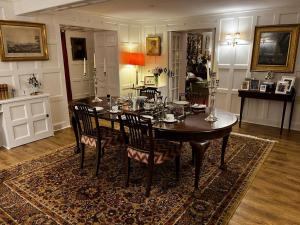 a dining room with a table and chairs on a rug at Whitehouse in Uplawmoor