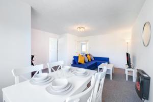 a dining room with a white table and a blue couch at 2 bed luxury apartment in Enfield