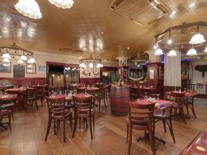 a restaurant with tables and chairs and a bar at Le Celtic in Le Thillay +10 photos