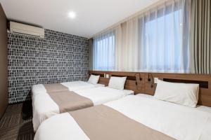 a bedroom with three beds and a window at Hotel Sanrriott Osaka Hommachi in Osaka