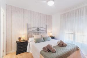 een witte slaapkamer met een bed met handdoeken erop bij Las Olas Chipiona in Chipiona