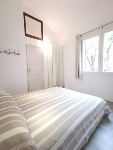 a white bedroom with a bed and a window at Appartamento due passi dal mare in Fort Village