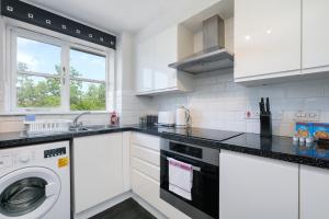 a kitchen with white cabinets and a washer and dryer at 2 bed luxury apartment in Enfield