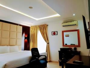 um quarto de hotel com uma cama, uma cadeira e um espelho em Brickland Residence em Abuja