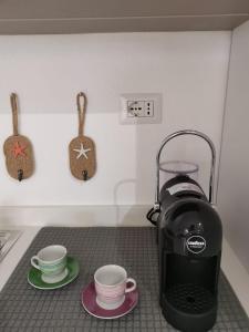 eine Kaffeemaschine und zwei Tassen auf der Theke in der Unterkunft Appartamento due passi dal mare in Fort Village