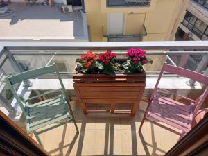two chairs and a table with flowers on a balcony at 365 Urban Suite in Heraklio Town