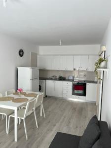 a white kitchen with a table and white cabinets at Theodoros Apt.79 in Paralimni