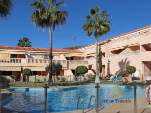 uma piscina em frente a um edifício com palmeiras em California Relax ALICE I POOL VIEW em Puerto de Santiago