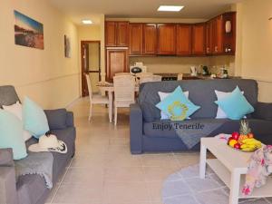 een woonkamer met twee blauwe banken en een keuken bij California Relax ALICE I POOL VIEW in Puerto de Santiago