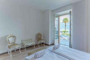 a bedroom with a bed and two chairs and a balcony at Maioliche Apartments Griante in Griante Cadenabbia