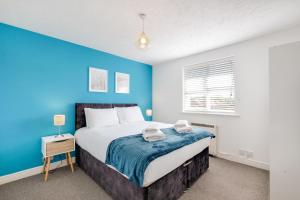 a bedroom with a blue accent wall and a bed at 2 bed luxury apartment in Enfield