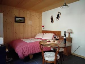 ein Schlafzimmer mit einem Bett und einem Tisch mit einem Glas Wein in der Unterkunft Chez Pierre in Praz-de-Fort