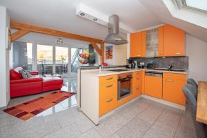ツェル・アン・デル・モーゼルにあるFerienwohnung Cellaのキッチン(オレンジ色のキャビネット、赤いソファ付)