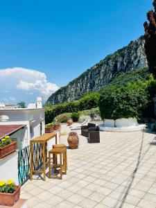 een patio met een tafel en stoelen en een berg bij B&B L'Agapanto in Capri