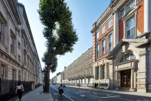twee mensen die fietsen door een straat met gebouwen bij Gower Street Houses, Fitzrovia, London in Londen