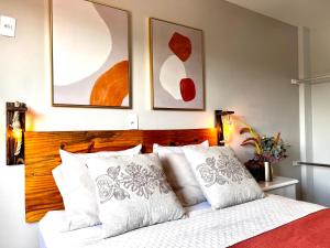 um quarto com uma cama com almofadas brancas e pinturas em Hotel APART Zuccolotto 201 em Aracruz