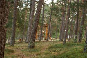 un parque infantil de madera en medio de un bosque en Merela guest house in Võsu centre en Võsu