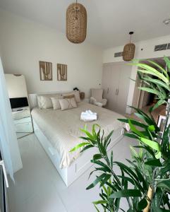 a white bedroom with a bed and plants in it at Tranquil Studio in Damac Hills in Dubai