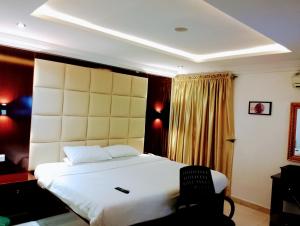 - une chambre avec un grand lit blanc et une chaise dans l'établissement Brickland Residence, à Abuja