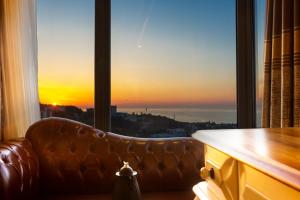 a couch in front of a window with a sunset at Andalouse Elegant Suite Hotel in Trabzon