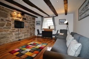 a living room with a couch and a stone wall at Watersedge Apartment- cosy home by the sea in Anstruther