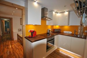 a kitchen with white cabinets and a red appliance at Watersedge Apartment- cosy home by the sea in Anstruther