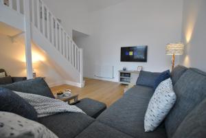 a living room with a blue couch and a tv at Walters Neuk Anstruther- luxury coastal home in Anstruther