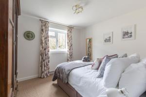 a bedroom with a bed with white sheets and a window at Luxury Cheltenham Home with EV charger - Lechampton Hills in Cheltenham