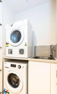 メルボルンにあるStylish Urban Oasisの洗濯機と電子レンジ付きのキッチン +1枚の写真