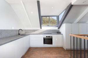 a kitchen with white cabinets and a sink and a window at Harbour facing Penthouse in Cape Town