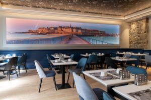 un restaurant avec des tables, des chaises et un grand écran dans l'établissement Hotel De L'univers, à Saint-Malo