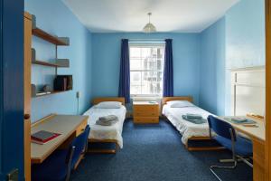 a room with two beds and a desk and a window at Gower Street Houses, Fitzrovia, London in London