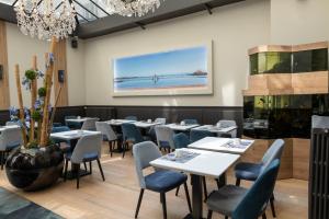 a restaurant with tables and chairs and a painting on the wall at Hotel De L'univers in Saint Malo