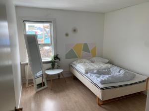 1 dormitorio con cama, mesa y ventana en Dejlig og et godt hus, Hotel en Sisimiut