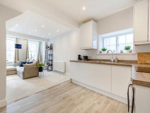 uma cozinha com armários brancos e uma sala de estar em Gate House Apartment em Westerham