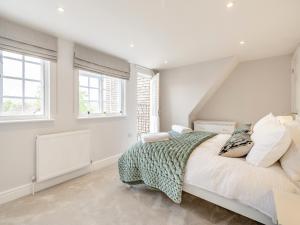 a white bedroom with a large bed and windows at Gate House Apartment in Westerham