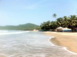 einen Sandstrand mit Palmen und dem Meer in der Unterkunft Cockerel Homestay - Traditional Beach Village - Goa in Canacona