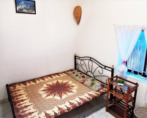 Un pequeño dormitorio con una cama con una alfombra. en Cockerel Homestay - Traditional Beach Village - Goa en Canacona