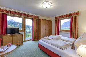 ein Hotelzimmer mit einem Bett, einem TV und Fenstern in der Unterkunft Hotel Babymio in Kirchdorf in Tirol