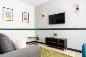 een woonkamer met een bank en een tv aan de muur bij Orange Rentals- 3 bed Scouse House Sleeps up to 8 guests in Liverpool