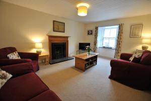 a living room with two red couches and a fireplace at Heron Cottage- fishermans cottage by the sea in Anstruther