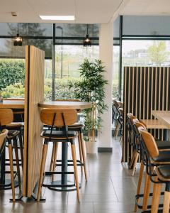 ein Restaurant mit Tischen, Stühlen und Fenstern in der Unterkunft Akena City Reims Bezannes in Reims
