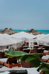 Martiness Hotel Durres في دوريس: مجموعة من الكراسي والمظلات على الشاطئ