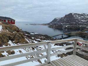 une maison rouge au sommet d'une montagne avec une masse d'eau dans l'établissement Dejlig og et godt hus, Hotel, à Sisimiut